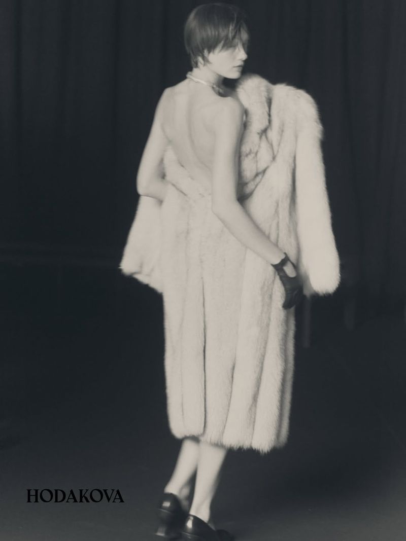 Model wearing a light fur coat and black gloves looking over shoulder in a black and white fashion editorial