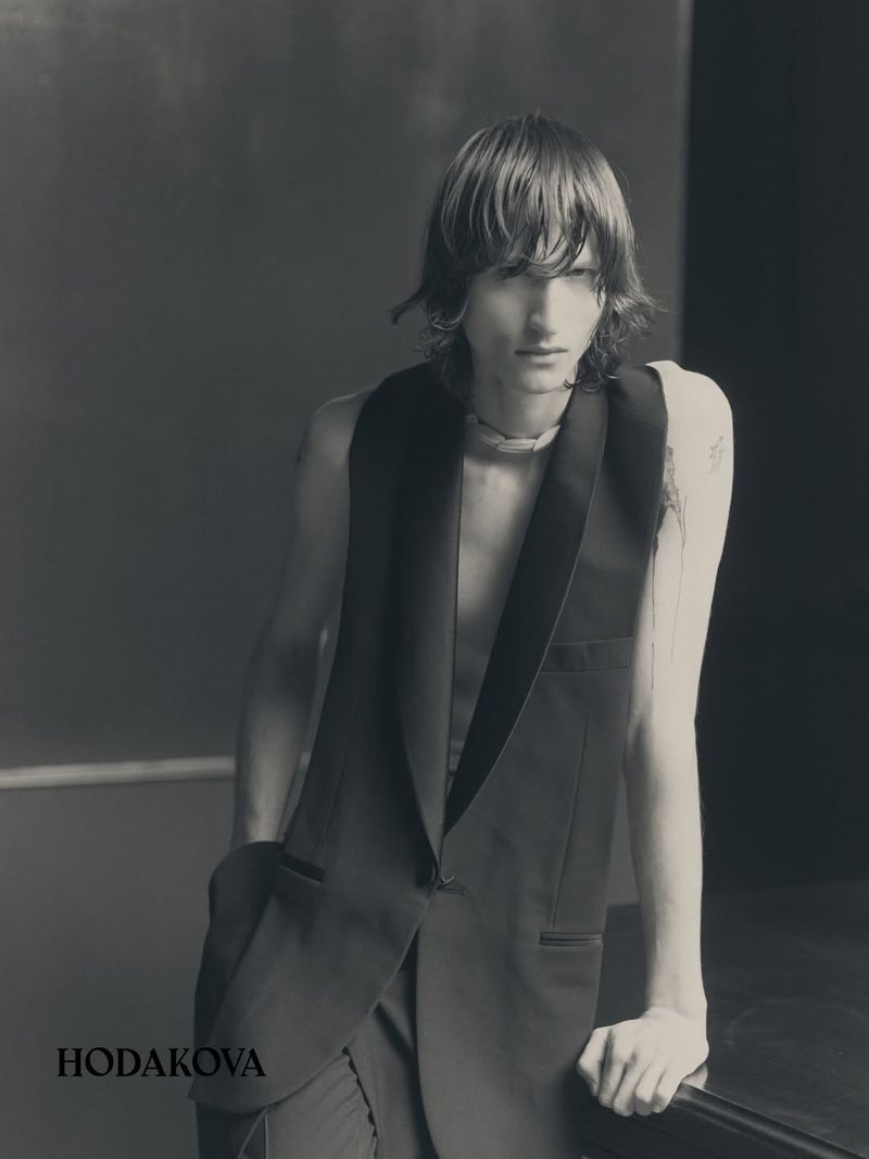 Monochrome fashion portrait of a model wearing a sleeveless tailored vest by Hodakova against a dark background