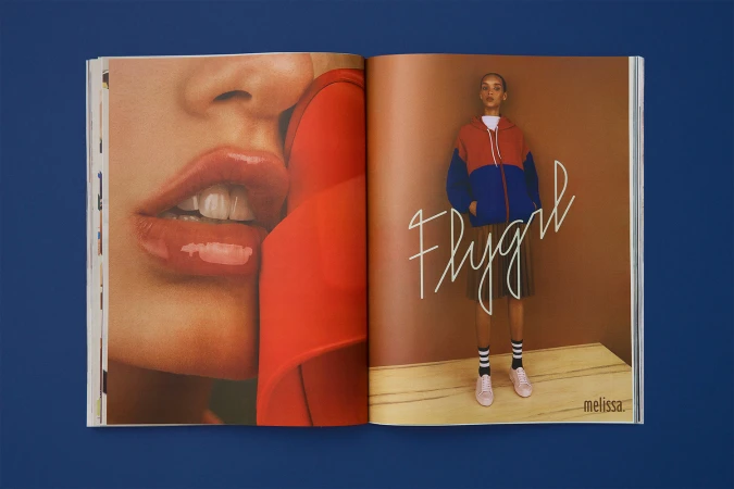 Open magazine spread showing a close-up portrait of lips on the left and a full-body model in a colorblock hoodie on the right.