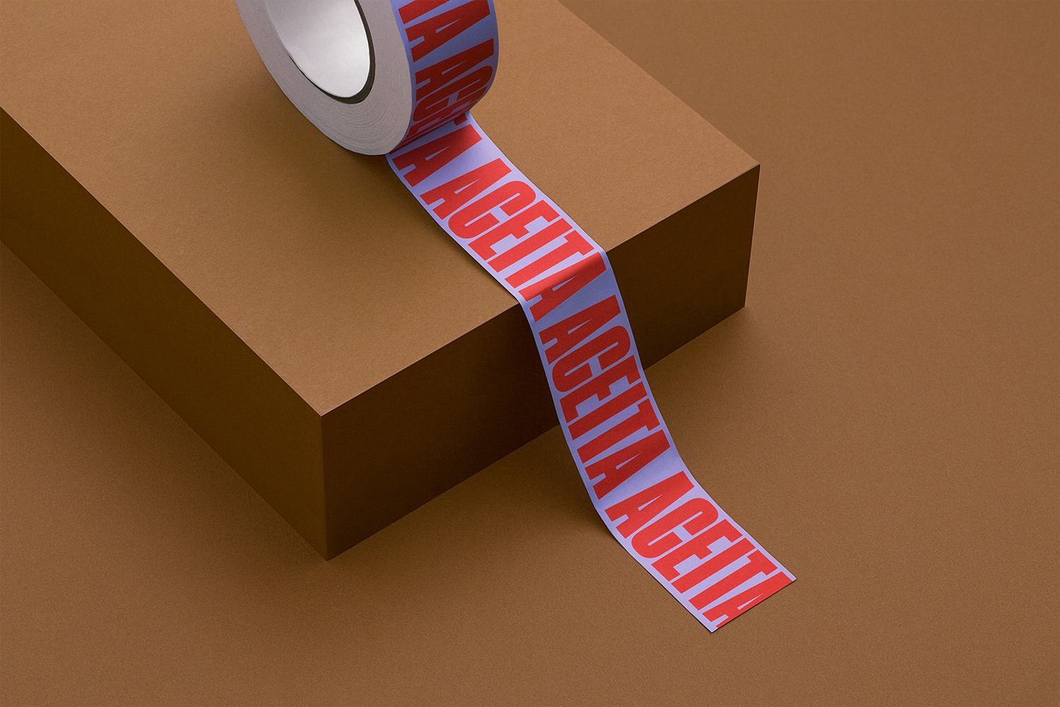 A roll of purple branded adhesive tape with red typography resting on a brown rectangular podium.