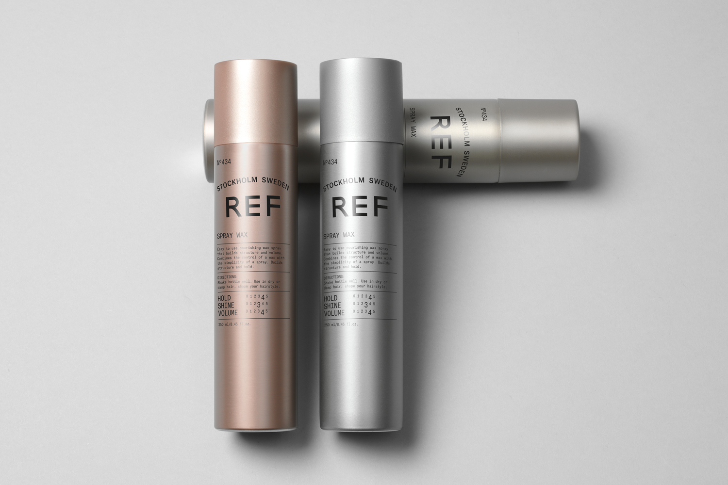 Three cylindrical REF Stockholm Sweden spray wax bottles arranged on a light grey background