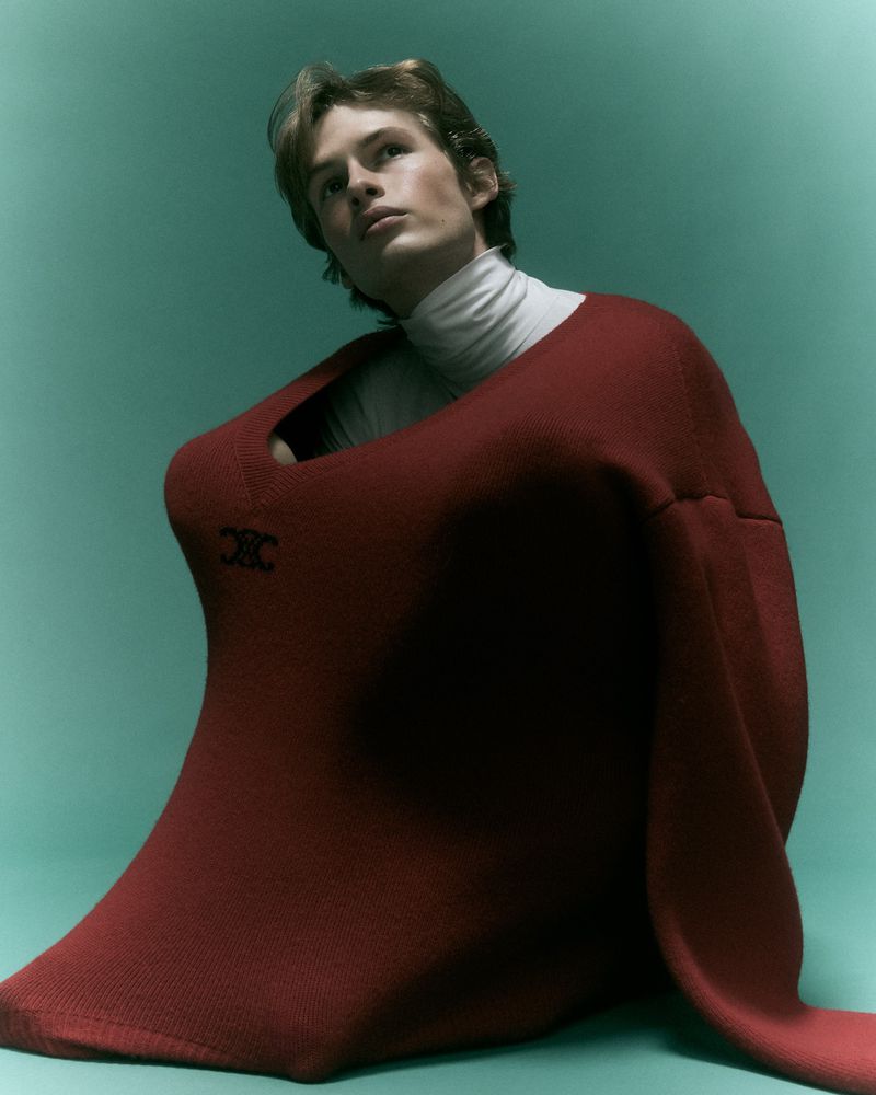 Model wearing an oversized red sweater and white turtleneck against a teal studio backdrop for Behind the Blinds Electric Feel editorial
