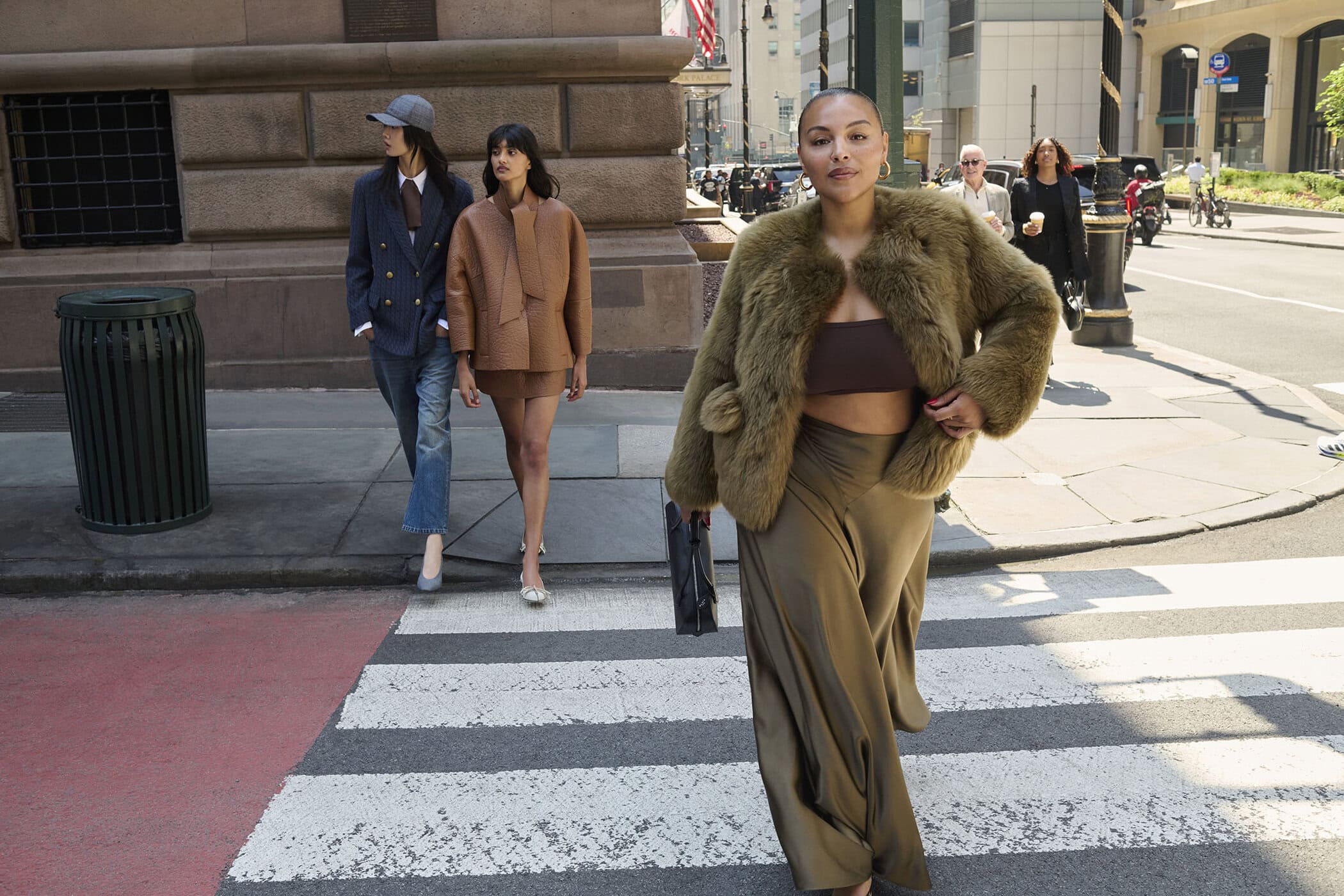 Three models walking across a city street crosswalk for the Saks Fifth Avenue fall 2025 ad campaign.