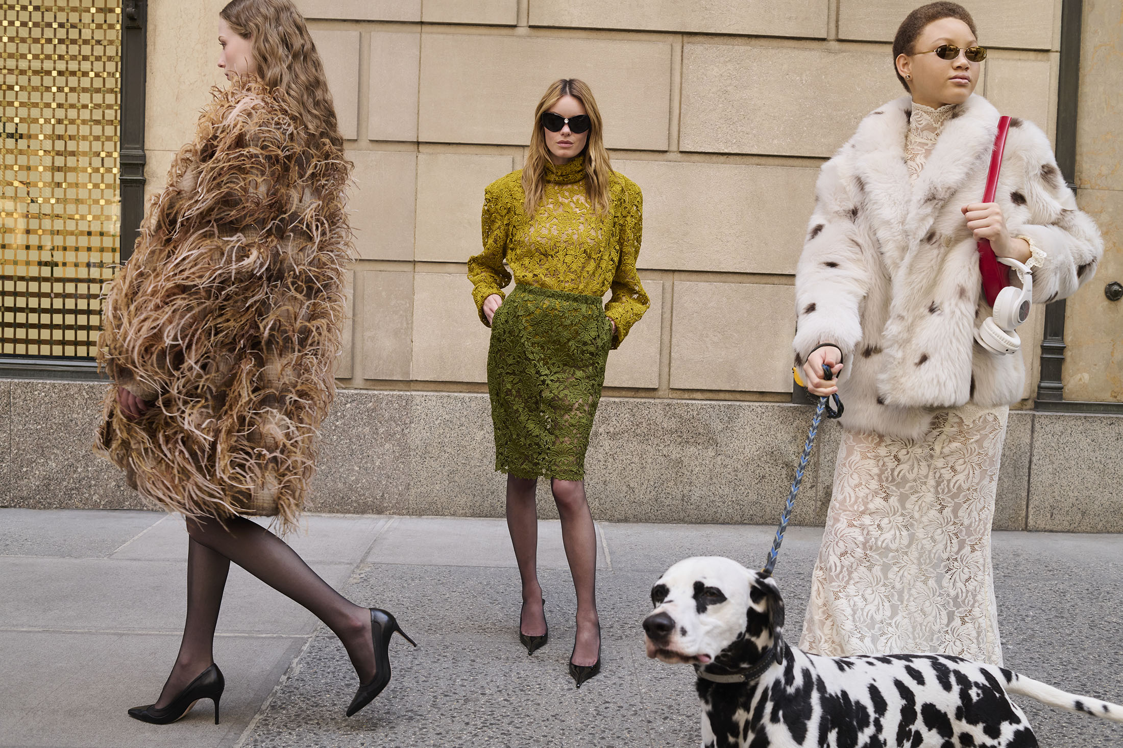 Three female models posing on a city street for Saks Fifth Avenue, accompanied by a dalmatian dog on a leash.