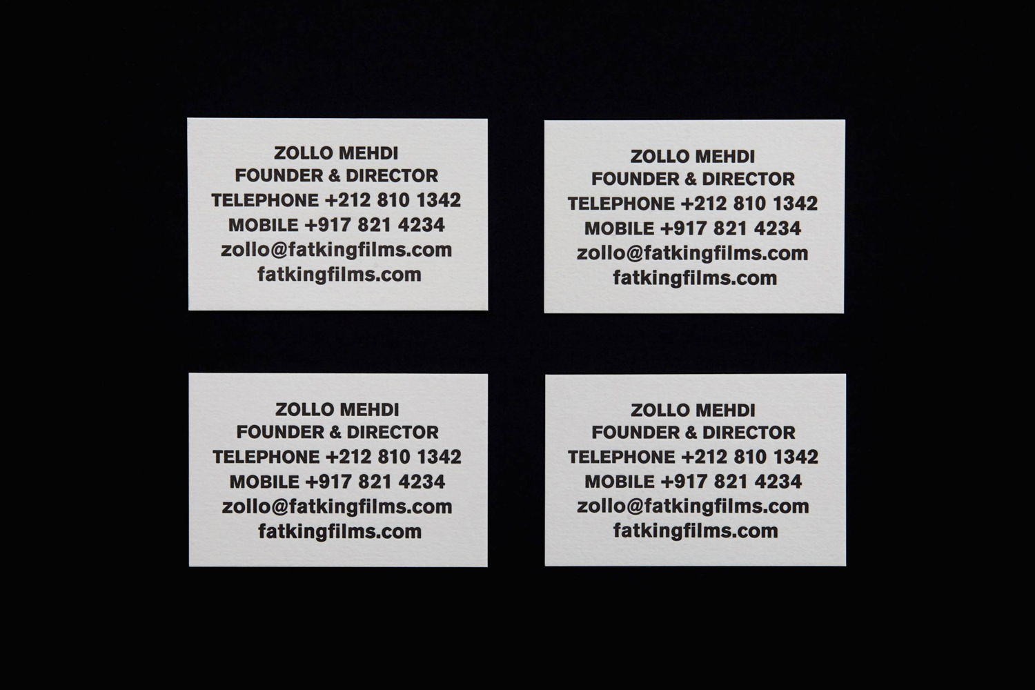 Four white business cards arranged in a grid with black typography against a dark background