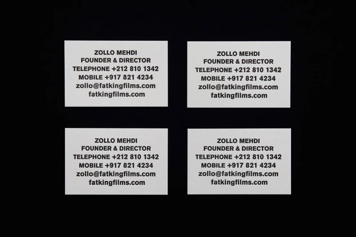 Four white business cards arranged in a grid with black typography against a dark background