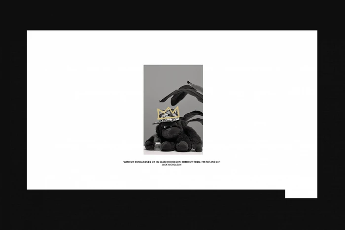 Black and white image of a plush gorilla wearing a patterned cap with a crown graphic, accompanied by quote text.