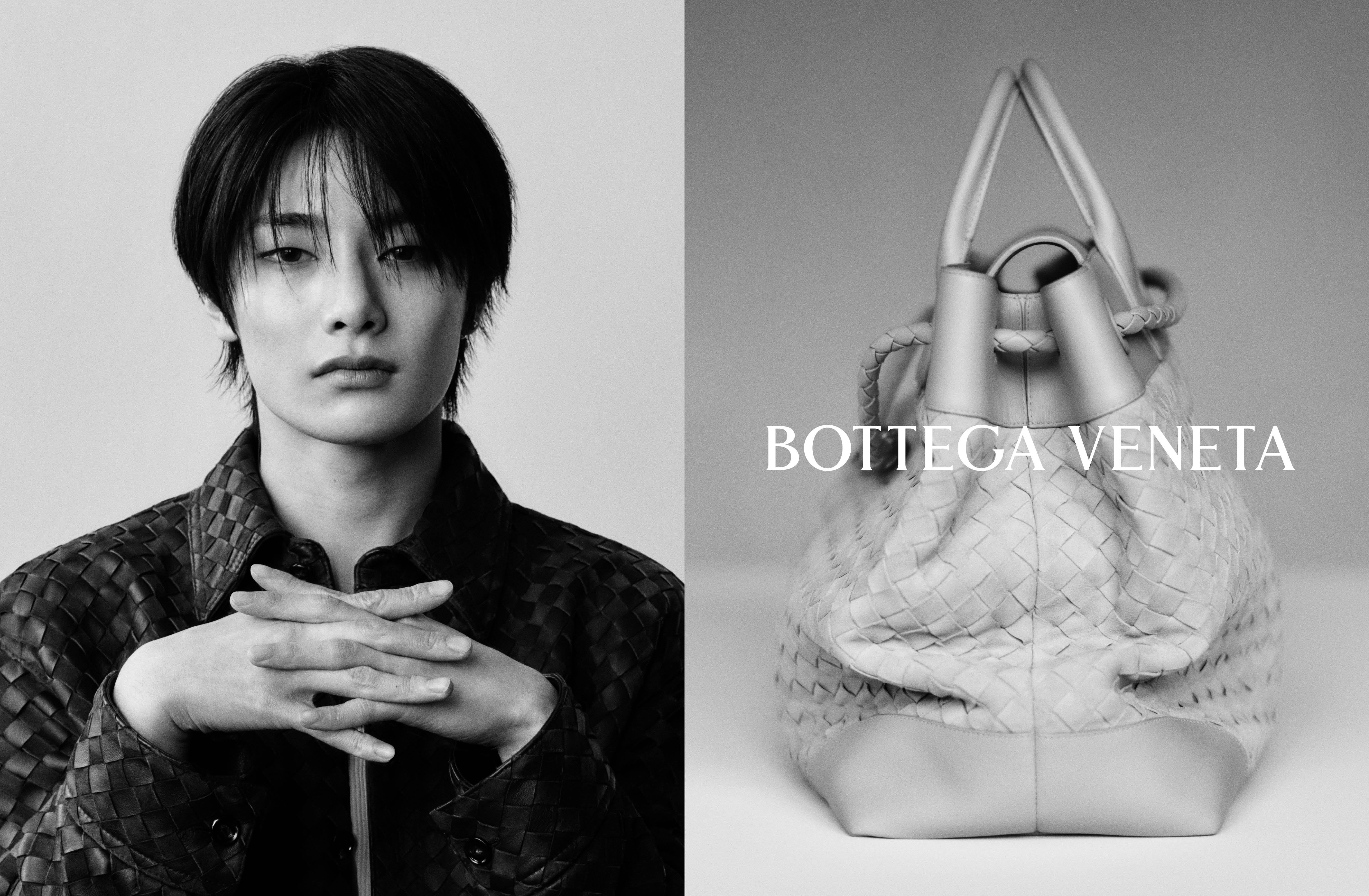 Black and white portrait of a man with dark hair posing with clasped hands next to a Bottega Veneta leather handbag.