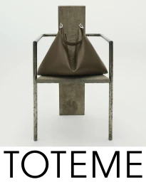 Brown leather handbag resting on a sculptural metal and stone chair against a plain white background for Toteme Fall 2025 ad campaign.