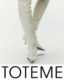 Close-up of a model wearing high white boots against a clean white seamless studio background for Toteme