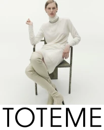 Model Julia Nobis seated in an armchair wearing a cream turtleneck dress and knee-high boots for Toteme Fall 2025 campaign.