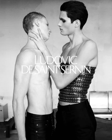 Two shirtless male models posing closely together in a monochrome fashion campaign image with visible brand typography.