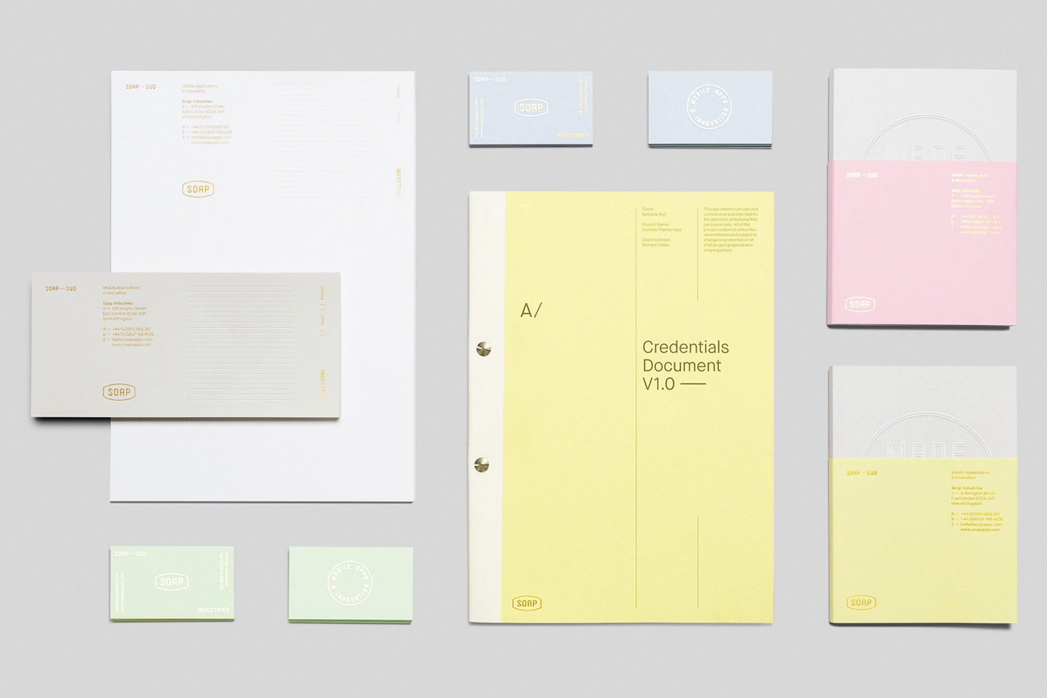 Flat lay of corporate identity stationery including letterhead, business cards, and bound documents on grey seamless background