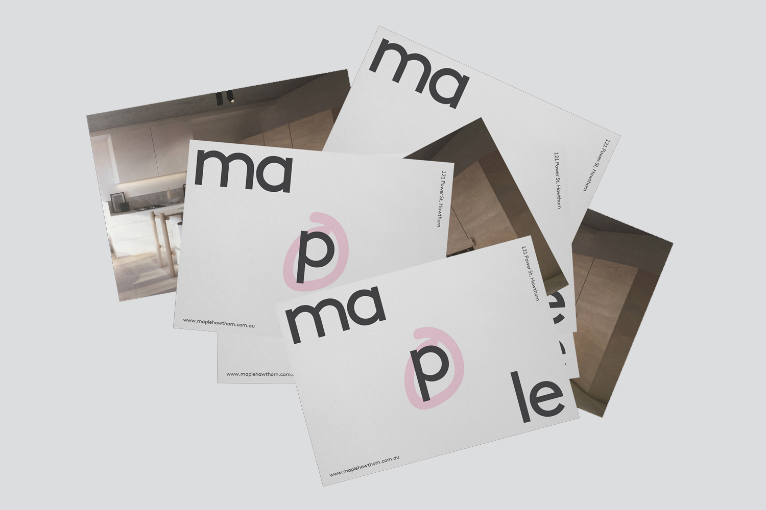 Scattered print cards displaying brand identity design with minimalist typography on white paper against a neutral background