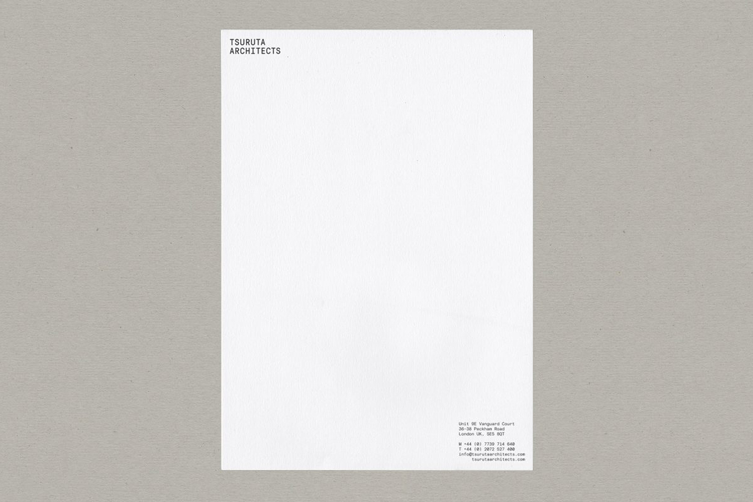 Minimalist white letterhead stationery design for Tsuruta Architects on textured grey surface