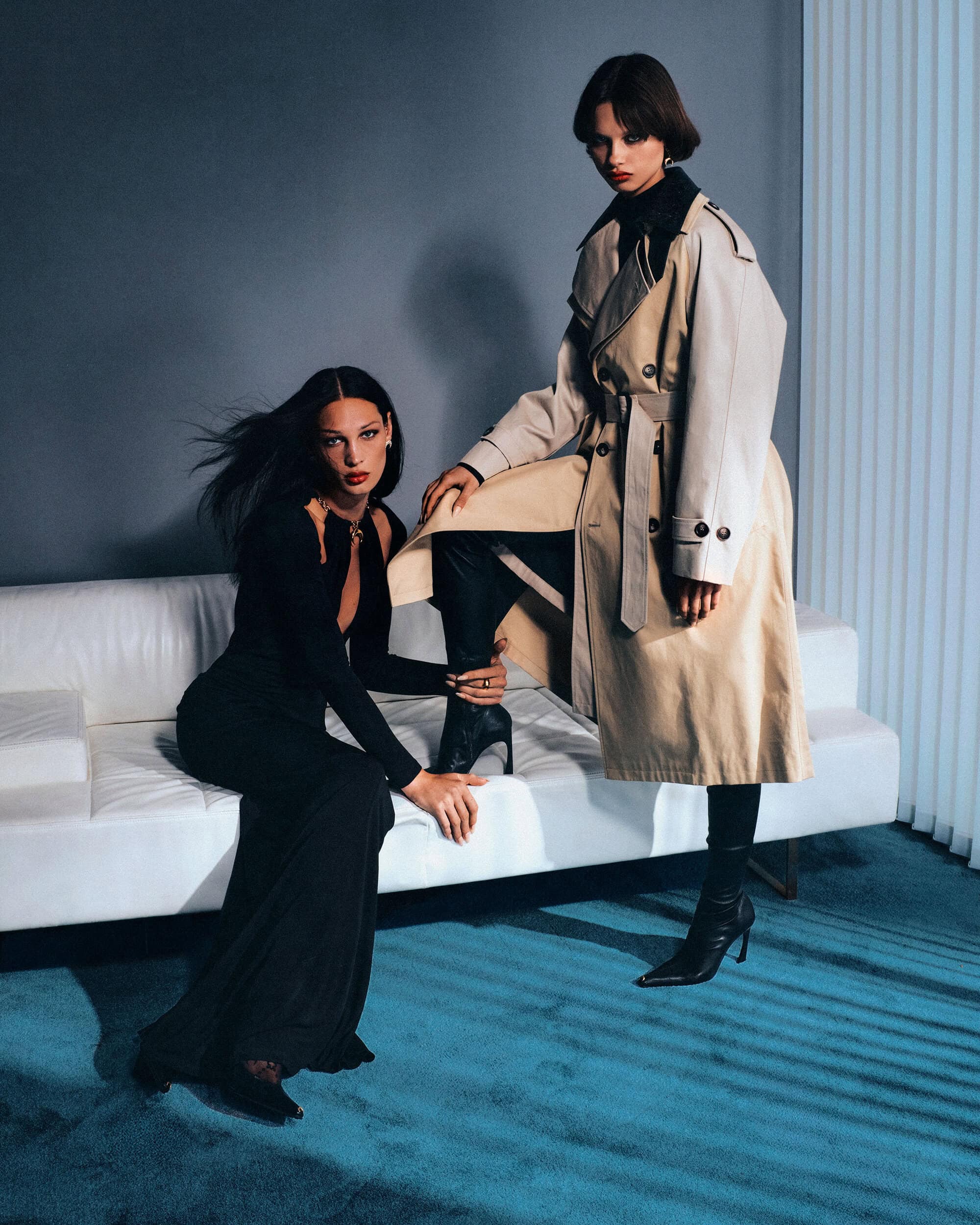 Two female models posing on a white sofa in a studio setting for the Marine Serre Fall 2025 campaign.