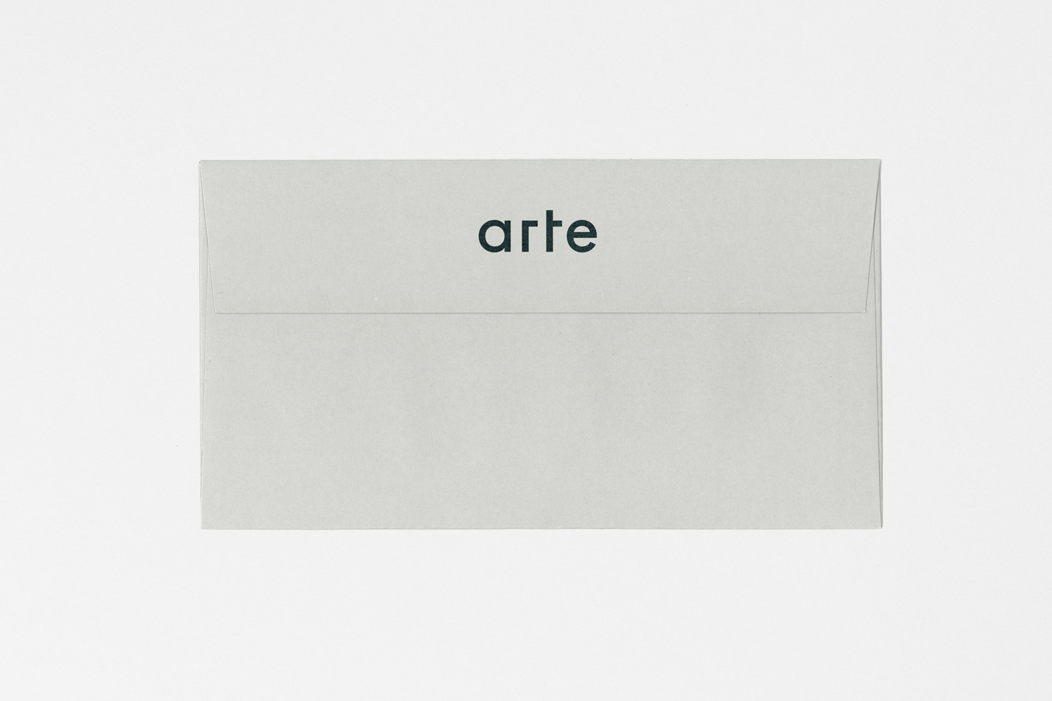 A light grey envelope centered against a plain white background with the word arte printed in dark green