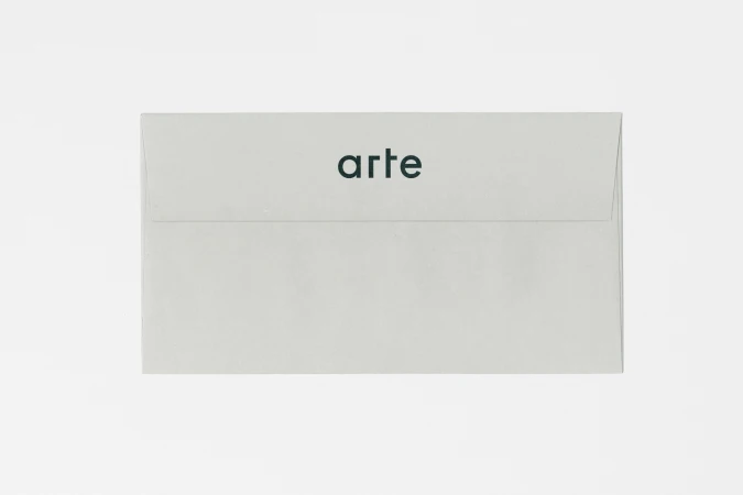 A light grey envelope centered against a plain white background with the word arte printed in dark green