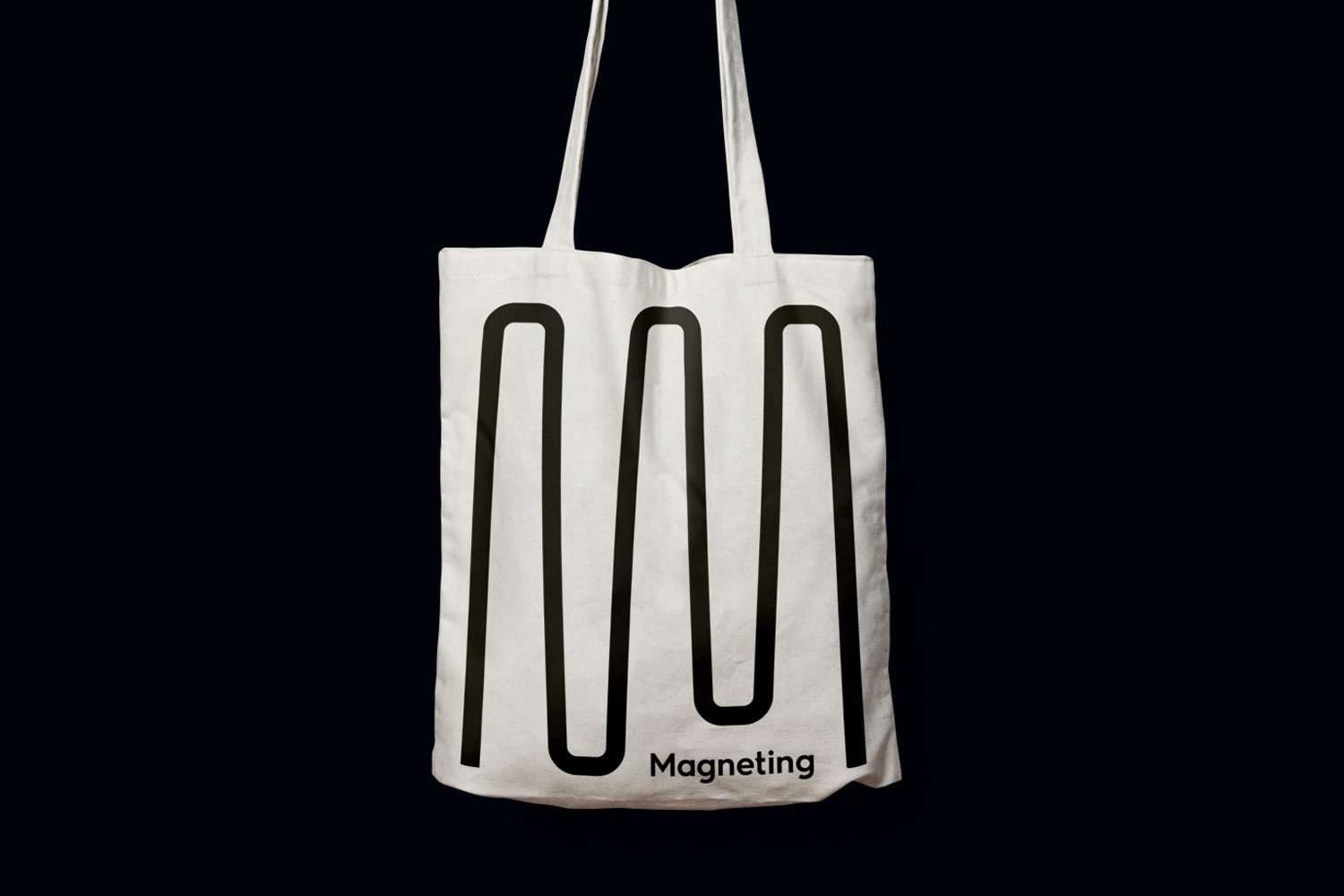 White canvas tote bag featuring a black wave graphic and Magneting logo against a dark background