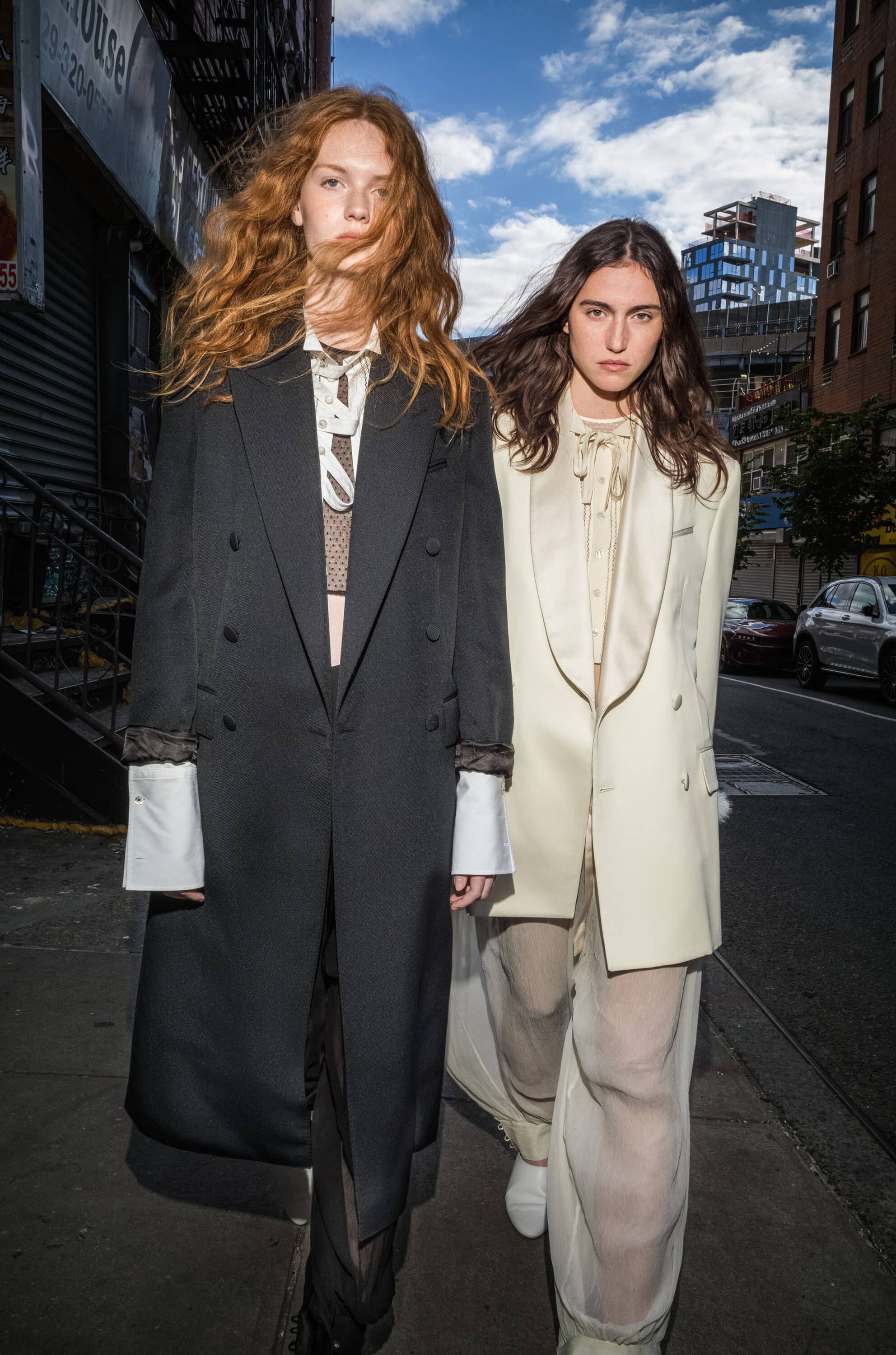 Two models walking down a New York City street wearing tailored coats for the Kenzo Fall 2025 ad campaign.