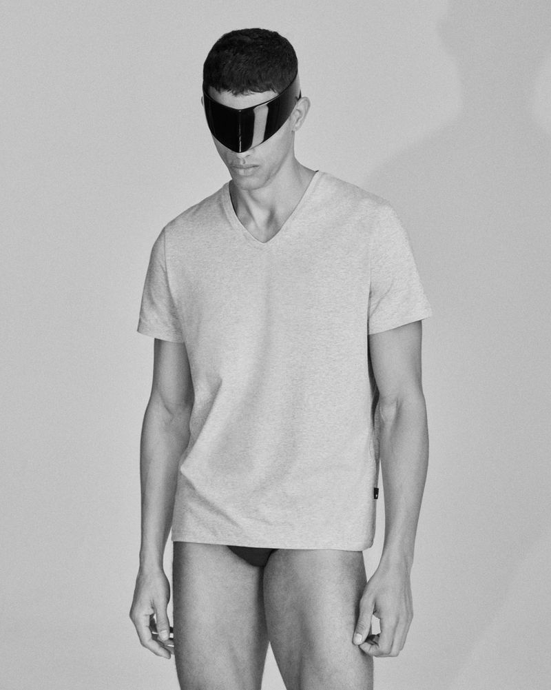 Portrait of a man wearing a t-shirt and futuristic visor in a studio with soft lighting and a neutral background in black and white.