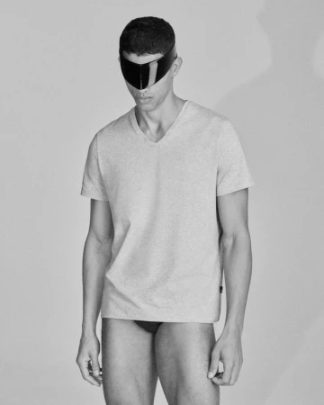 Portrait of a man wearing a t-shirt and futuristic visor in a studio with soft lighting and a neutral background in black and white.