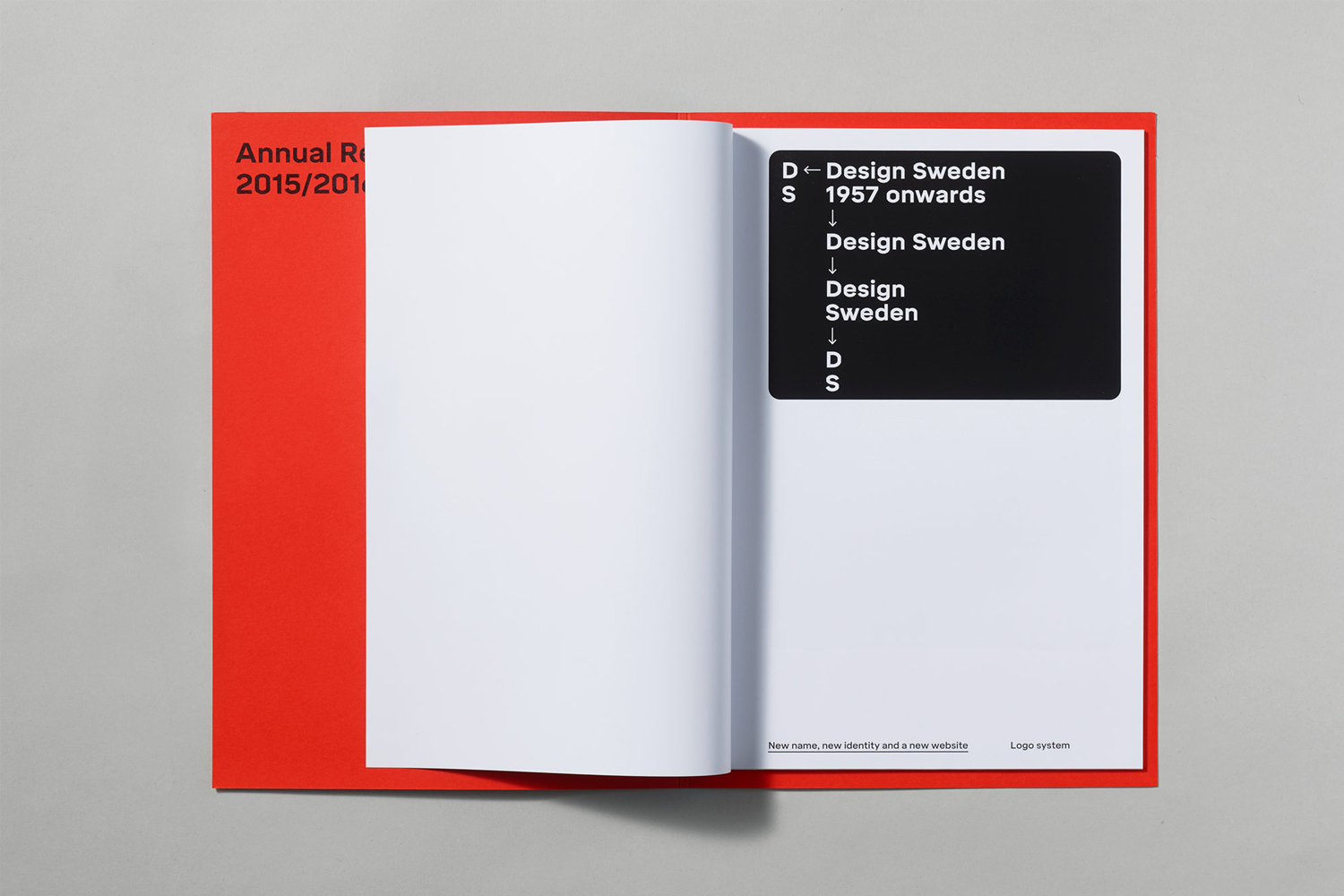 Open brochure displaying typography and a black logo system card against a red cover and grey surface background