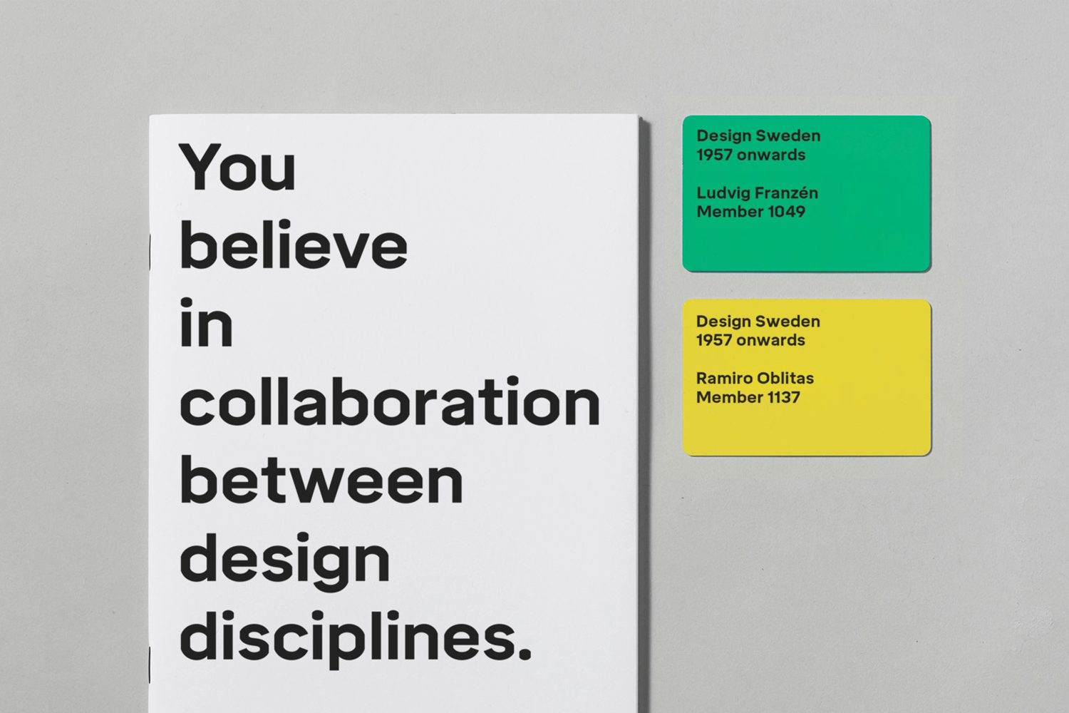 White book with bold black typography next to two colored membership cards on a gray surface