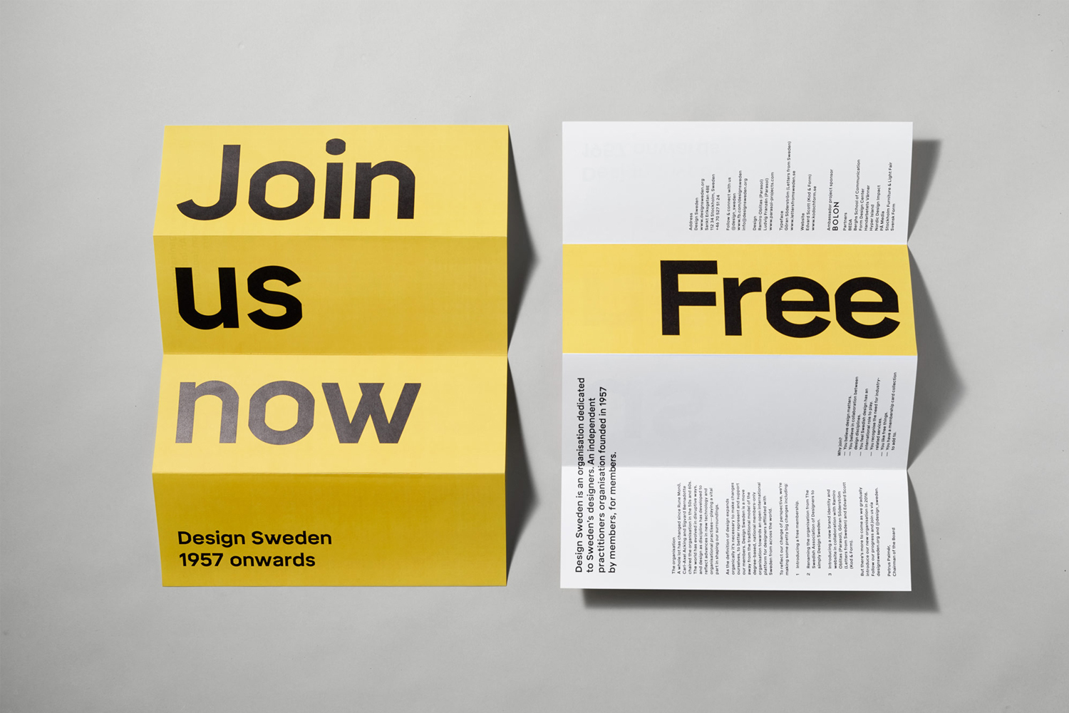 Two folded brochures featuring bold black typography against yellow and white backgrounds, shot overhead on grey.