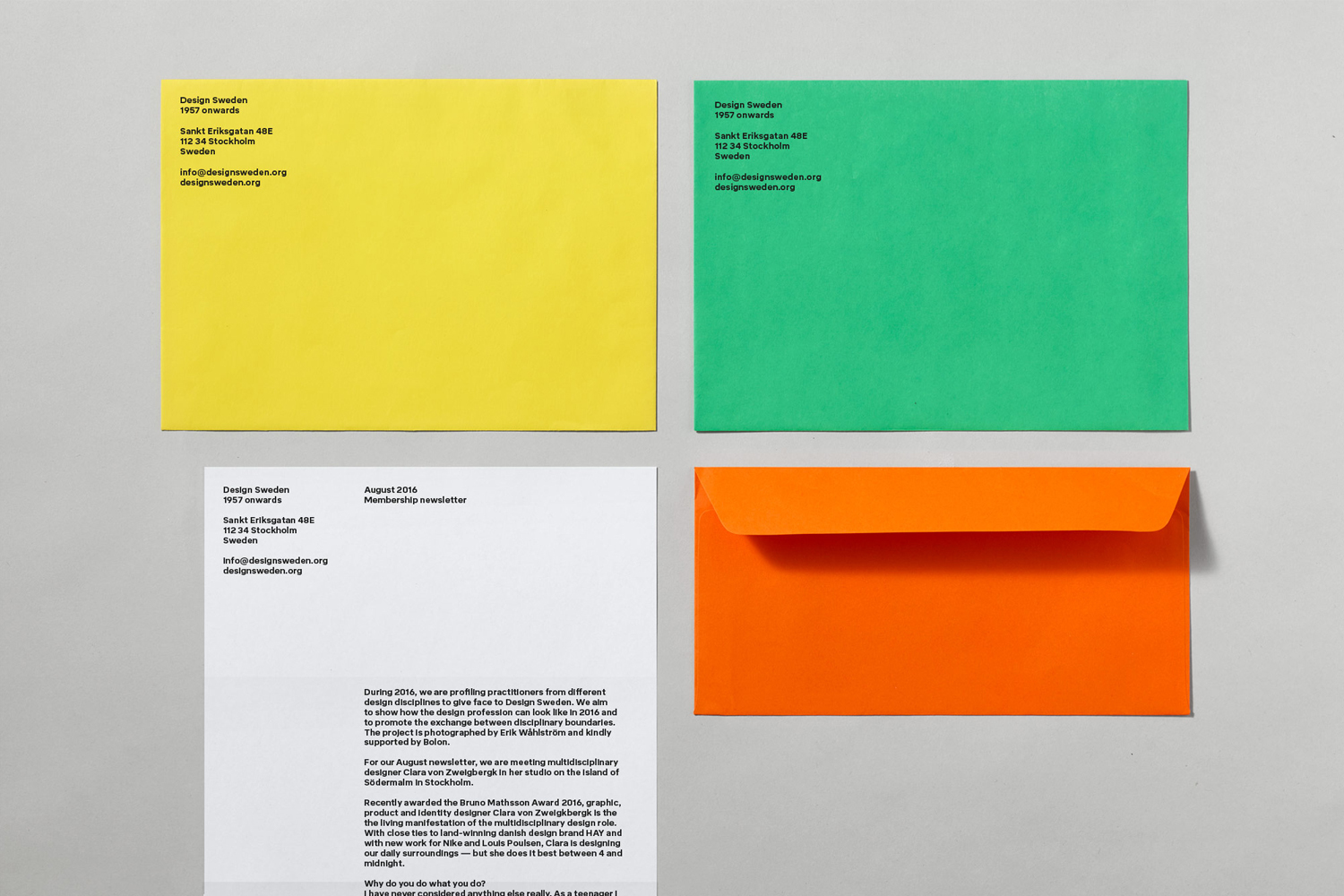 Top-down view of yellow, green, and orange envelopes alongside printed stationery on a grey surface for Design Sweden