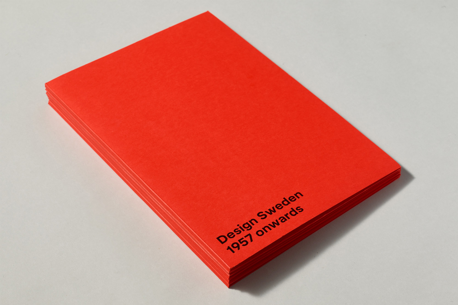 Vibrant red booklet with black typography resting on a clean white surface