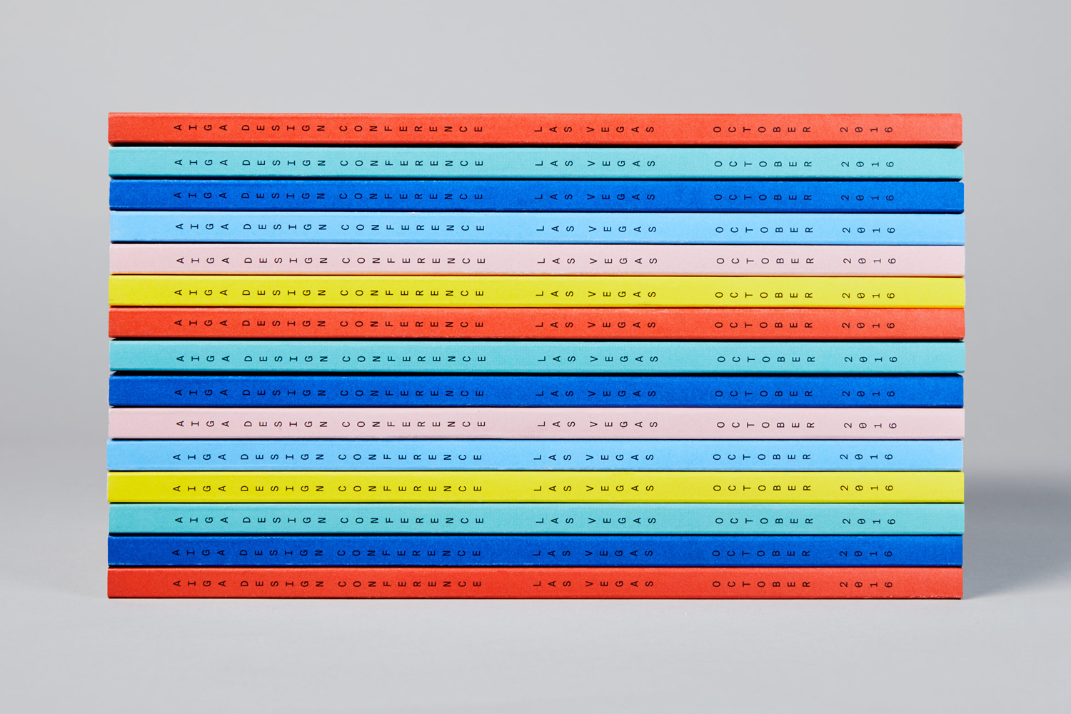 A stacked pile of colourful books featuring typographic text on the spines against a light grey studio background.