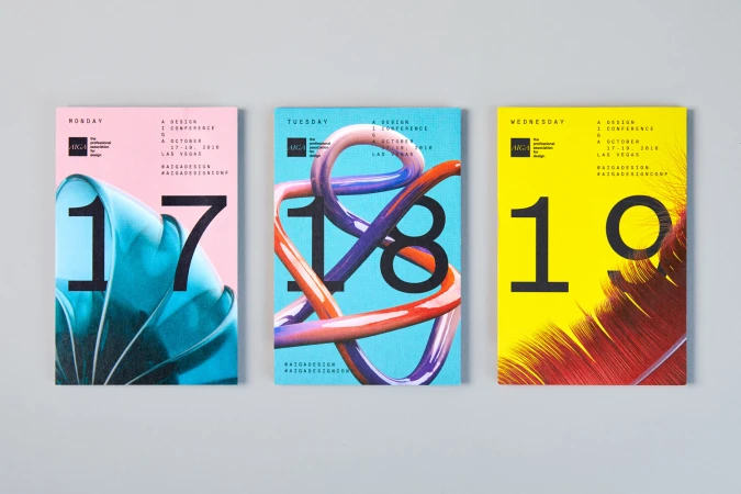 Three colorful graphic design conference brochures featuring numbers 17, 18, and 19 displayed flat on a grey surface.