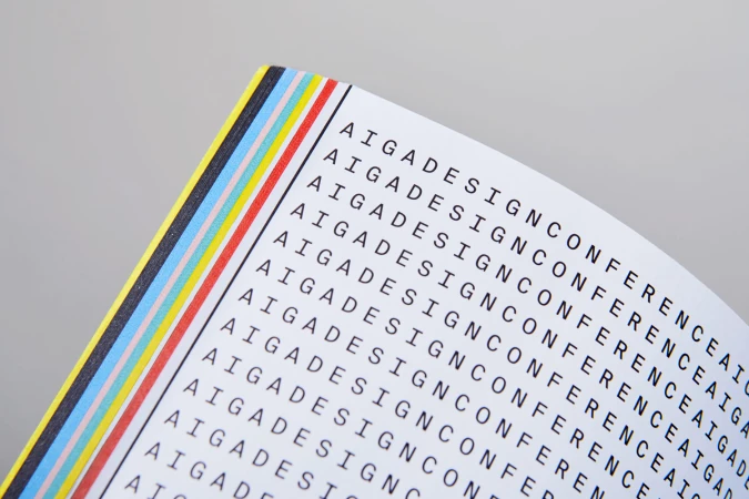 Close-up of a printed publication edge showing repeated typography and vibrant colored stripes