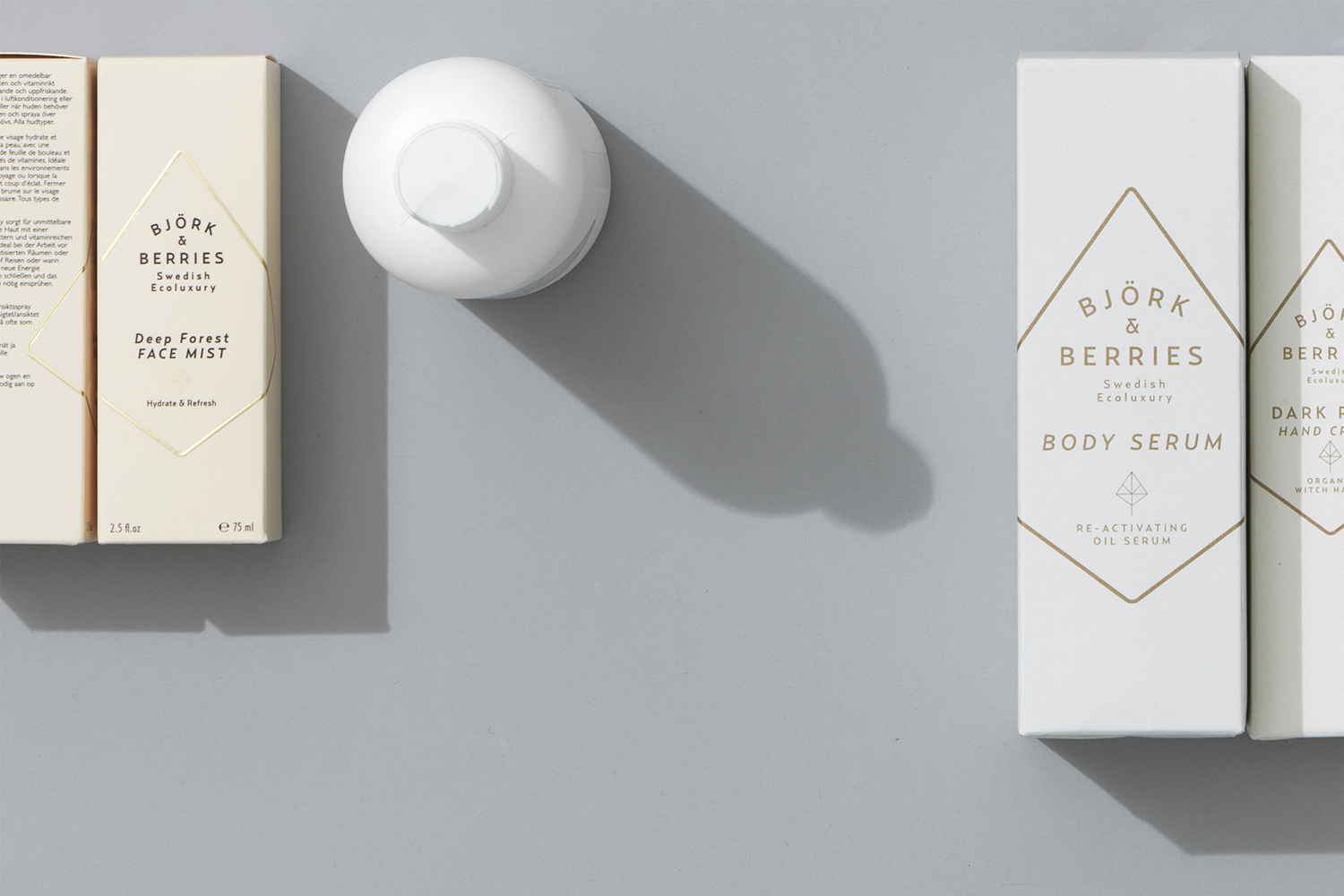 Bjork & Berries skincare bottles and product boxes arranged on a pale grey studio background