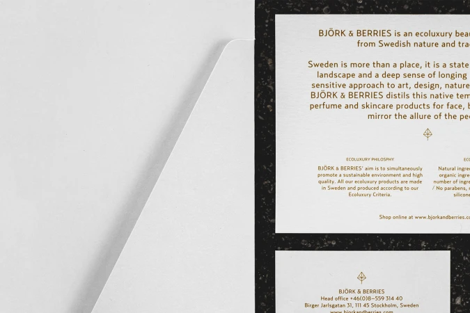 White paper stationery with gold typography and brand text resting on a dark textured background