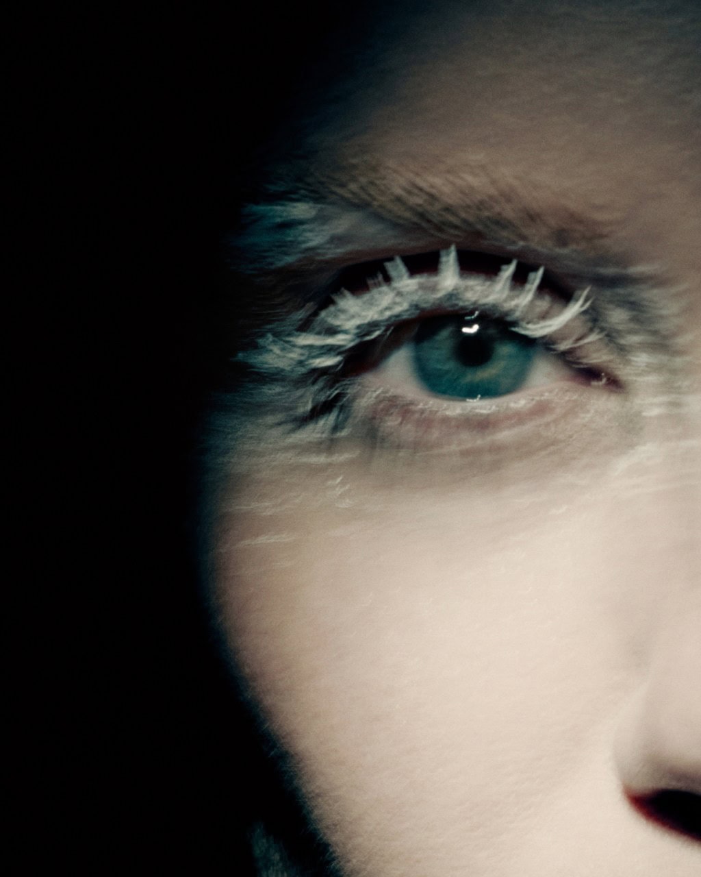 Close-up portrait of a woman's blue eye with white frosted eyelashes for Maison Margiela Fall 2025 campaign.