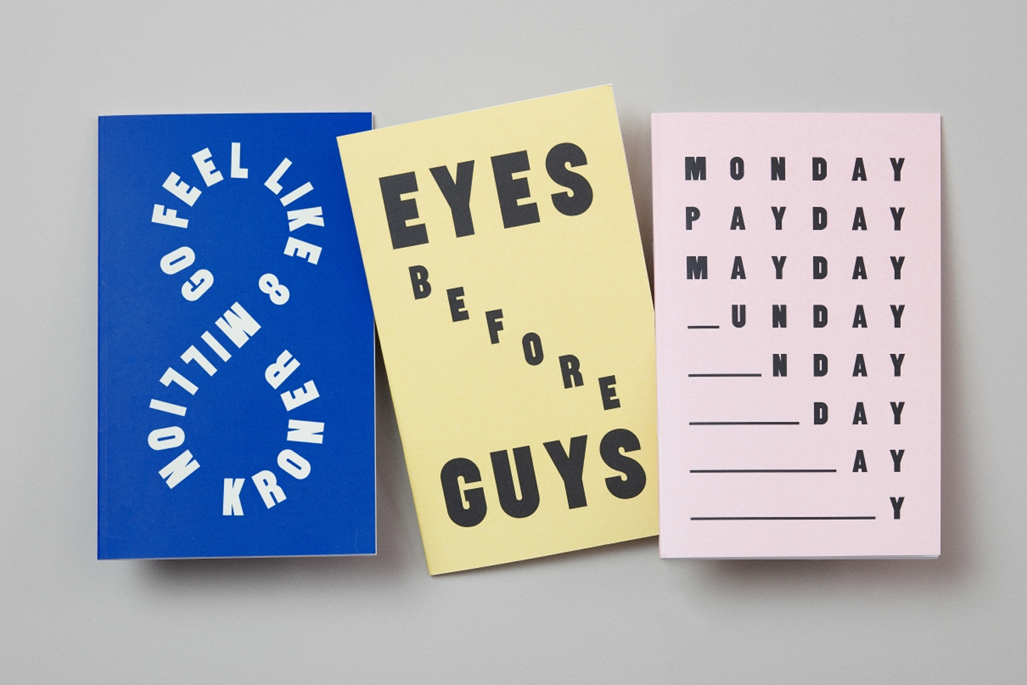 Three colorful notebooks with bold typography displayed on a neutral grey background for Kaibosh brand identity