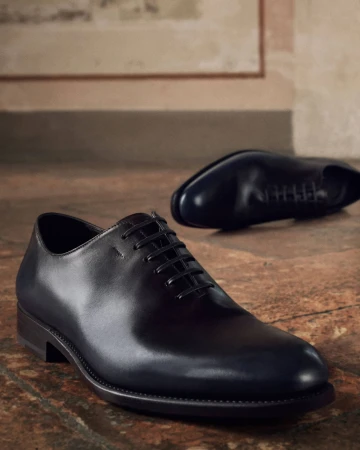 Close-up of polished black leather dress shoes placed on a textured floor surface
