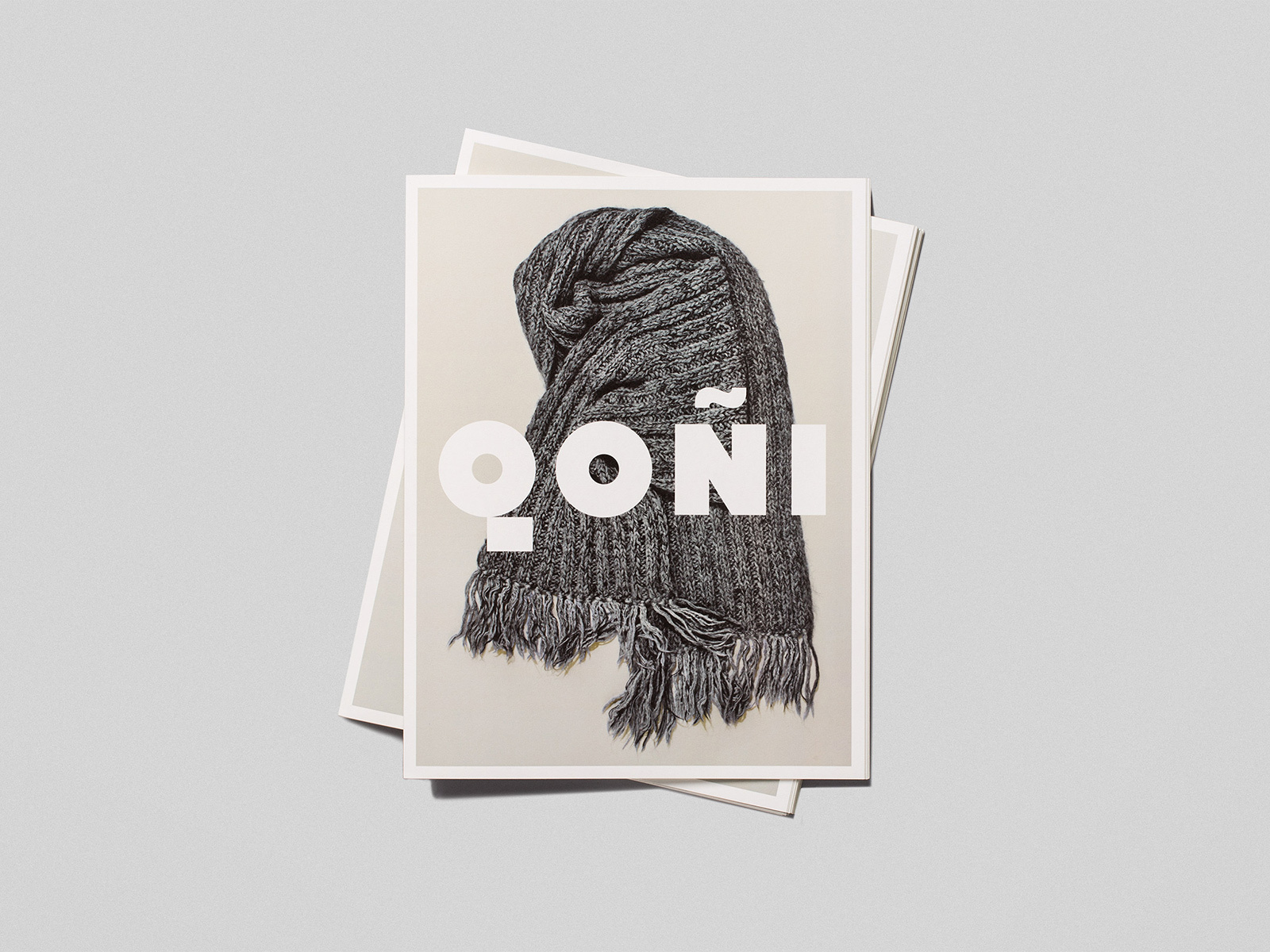 Stacked promotional prints featuring a dark grey knitted scarf with fringe and bold white Qoni typography on a grey background