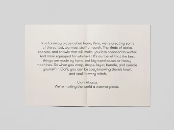 Open pamphlet with centered typography on a pale textured paper background for Qoñi brand identity