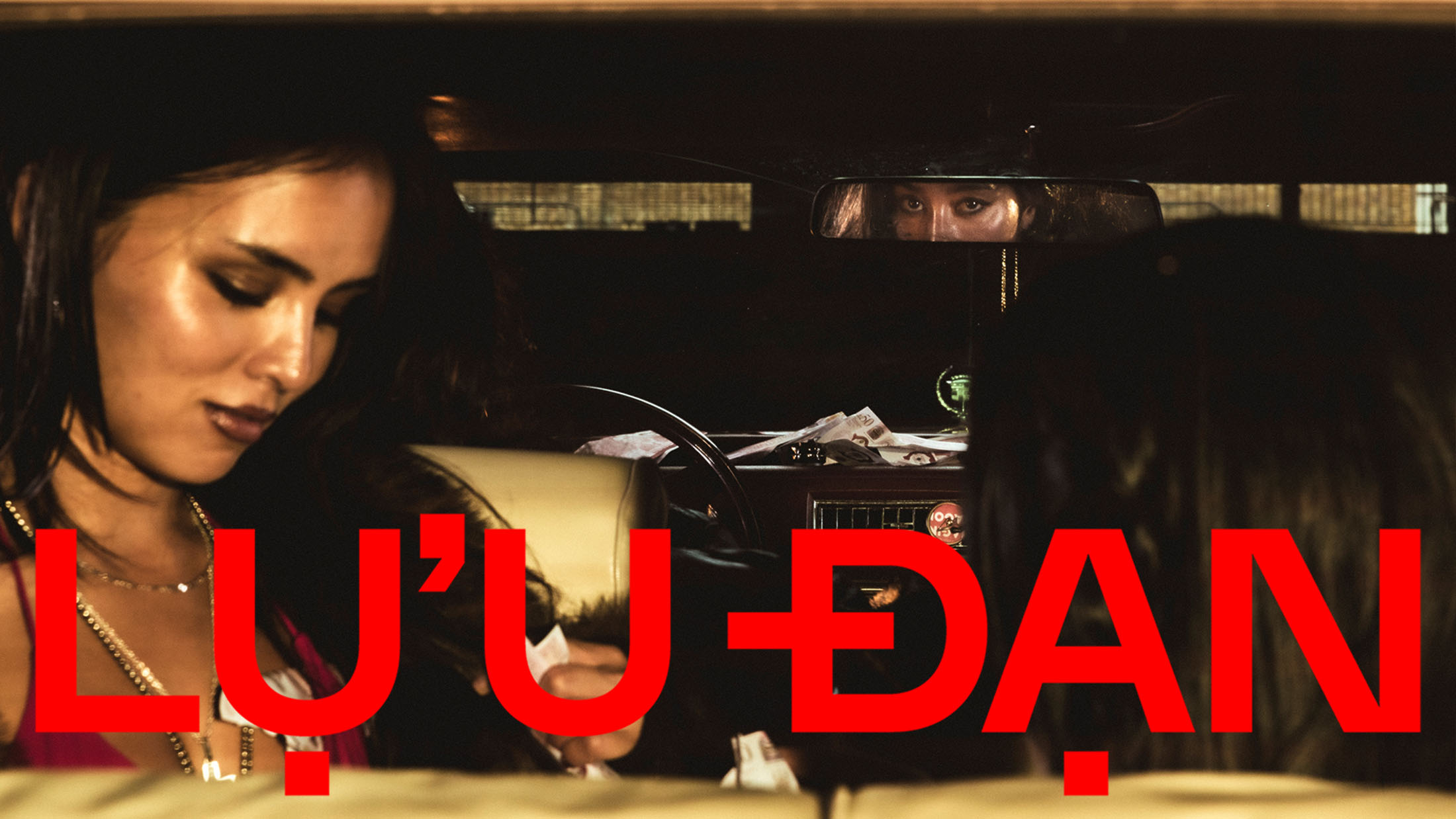 Two women seated inside a car at night with bold red Lu'u Dan brand text overlaid across the lower frame.