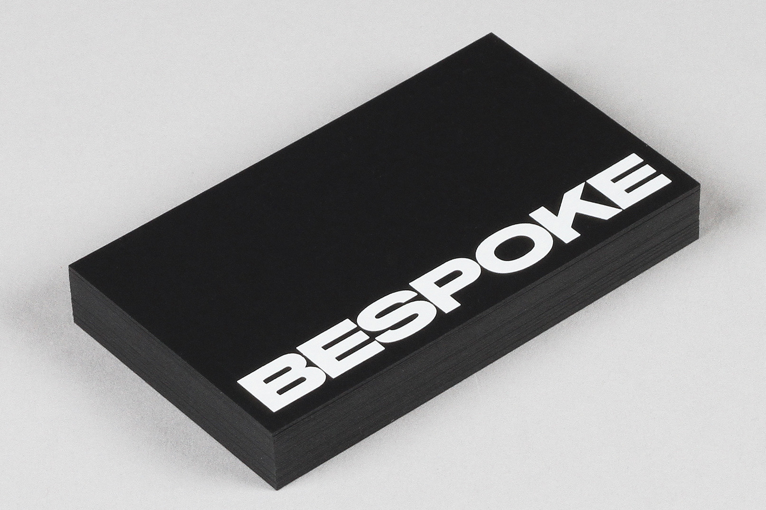 A stack of black business cards featuring bold white uppercase typography reading Bespoke against a light grey background.