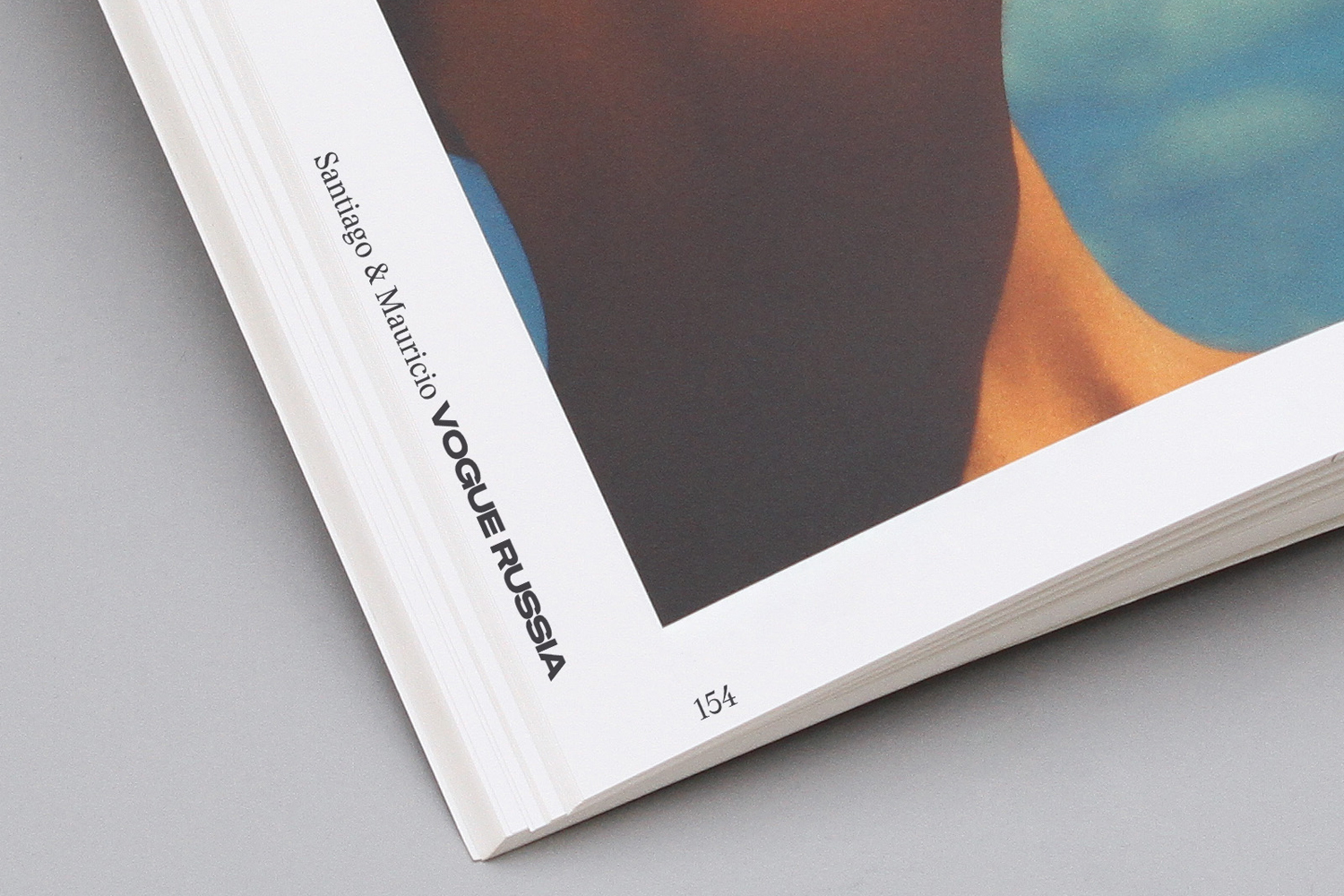 Close-up angled view of an open magazine page showing typography credits and a page number on a grey background