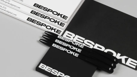 Bespoke brand identity stationery flat lay with black pens, notebooks, and letterhead featuring bold typography.