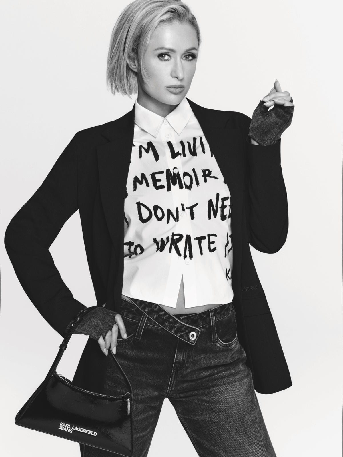 Paris Hilton in a black blazer, slogan shirt, and dark jeans holding a black handbag for Karl Lagerfeld