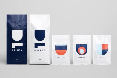Five minimalist coffee packaging bags with bold blue, white, and red geometric typography against a light grey background.