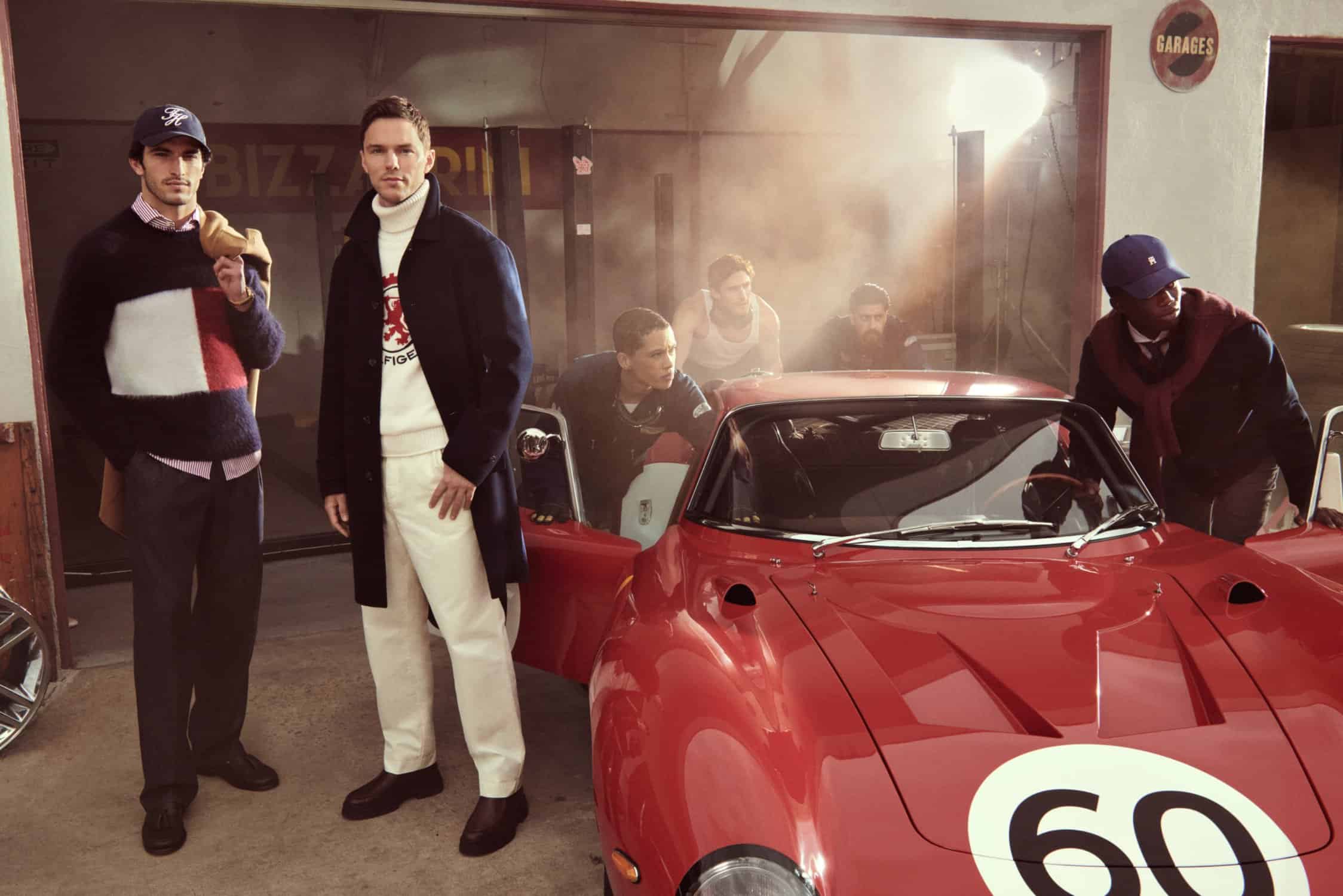 Group of six models posing around a vintage red sports car inside a garage for Tommy Hilfiger Fall 2025 campaign