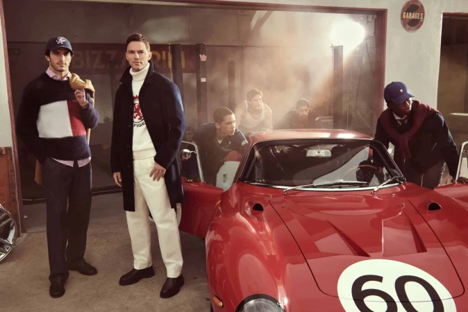 Group of six models posing around a vintage red sports car inside a garage for Tommy Hilfiger Fall 2025 campaign