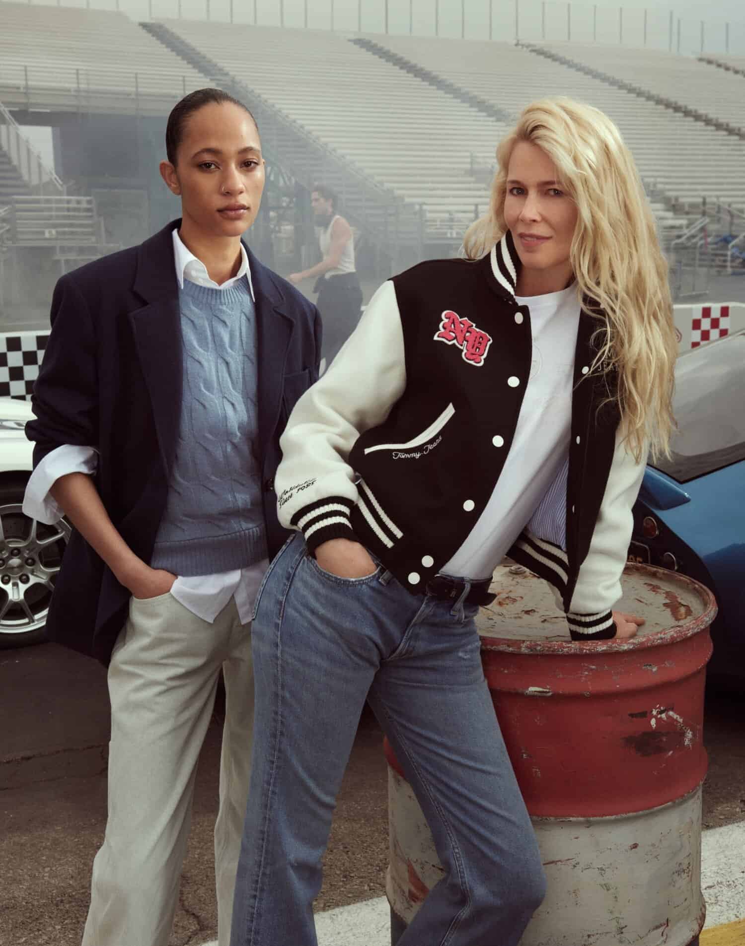 Claudia Schiffer and another model wearing casual apparel posing outdoors near a race track for Tommy Hilfiger Fall 2025 ad campaign.